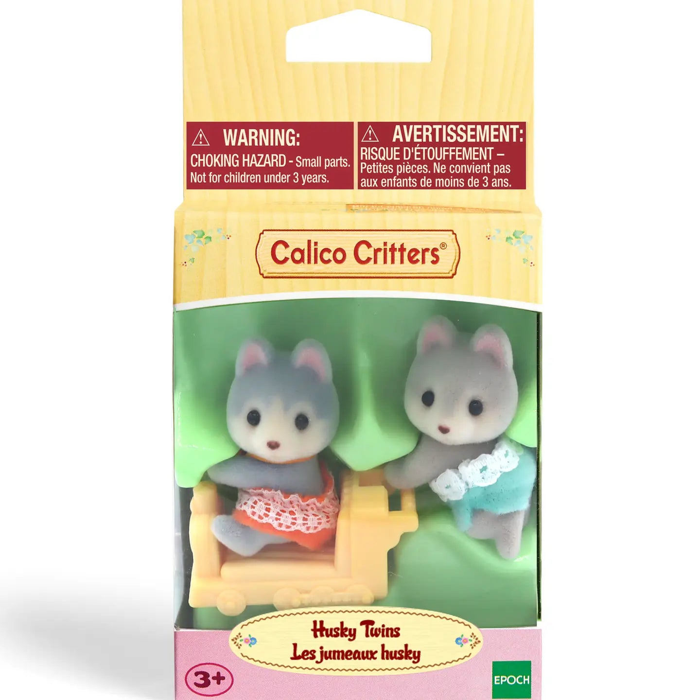 Packaged Calico Critters Husky Twins, with one doll figure in a red dress and the other in a blue outfit, pulling a small car.