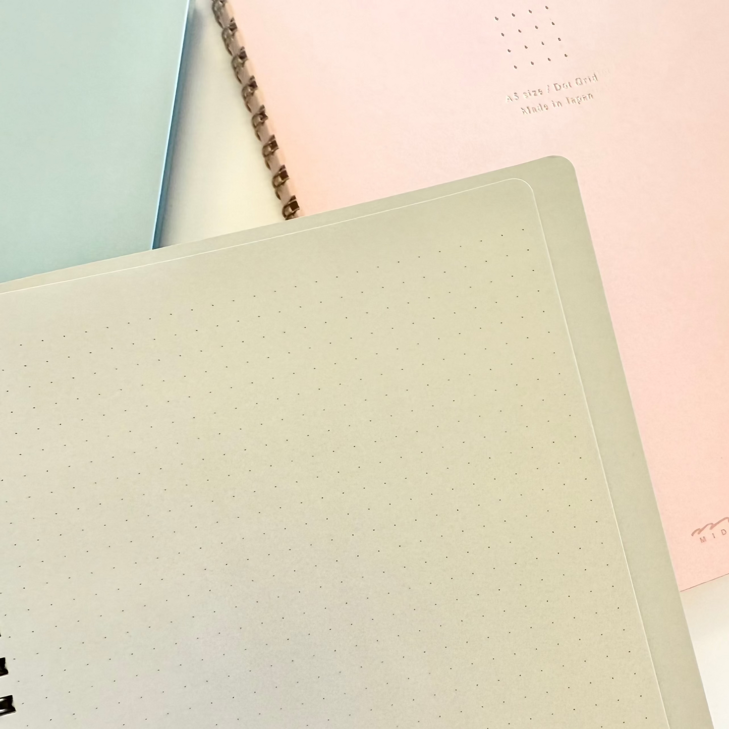 Three notebooks in pastel colors stacked on top of each other.