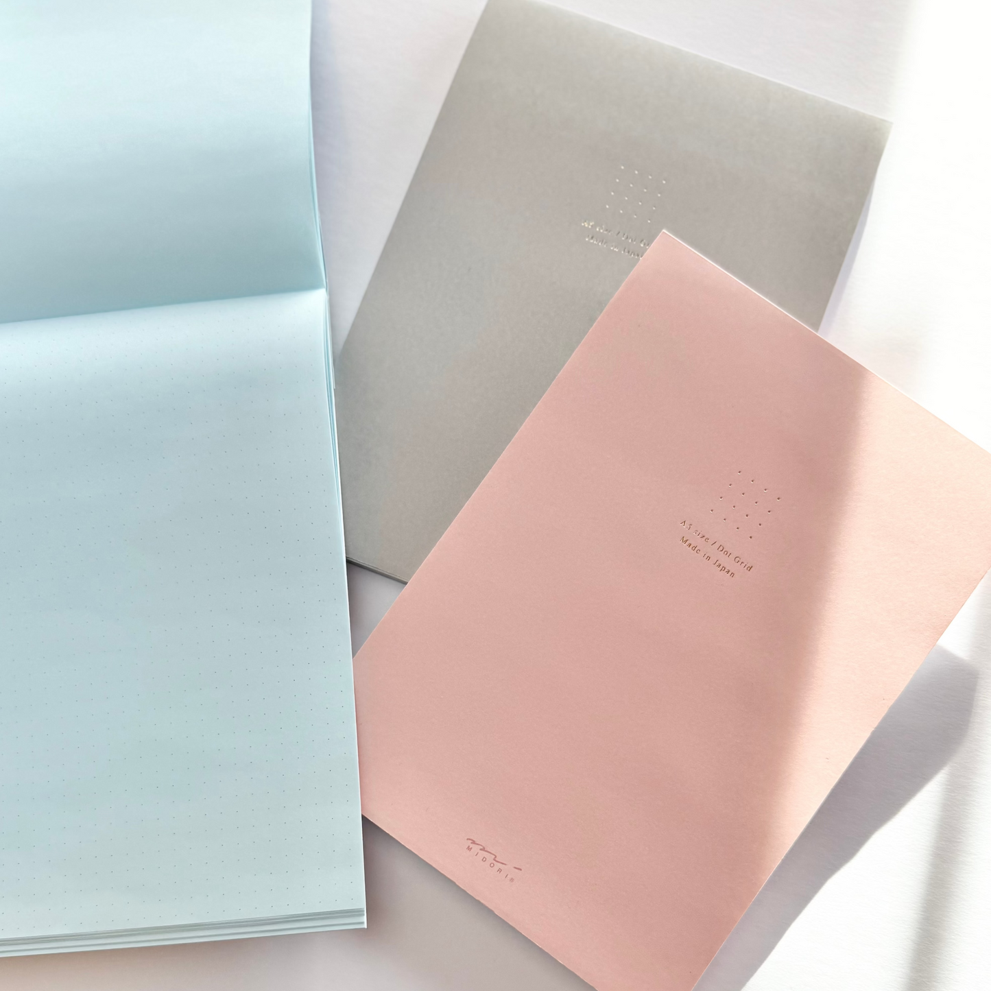 Three notebooks in pastel colors on a light background