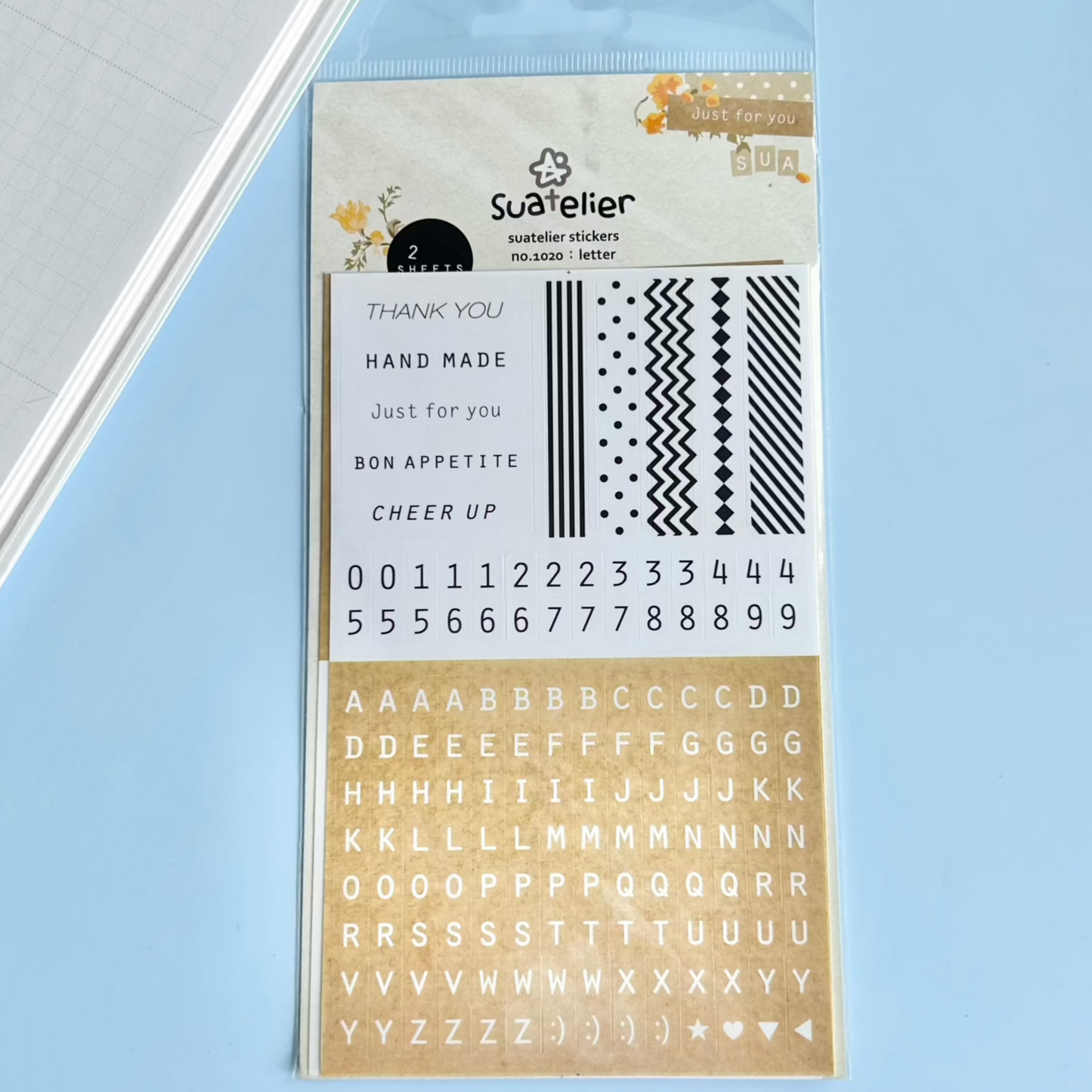 Sheet of decorative stickers with text and patterns on a light blue background