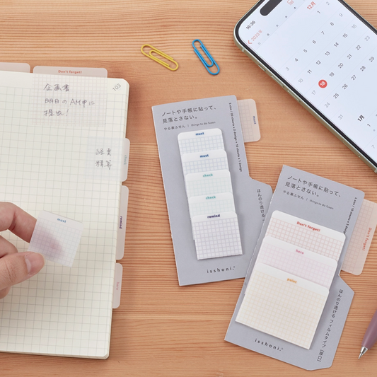Note-taking setup with notebooks, sticky notes, and a smartphone on a wooden surface.