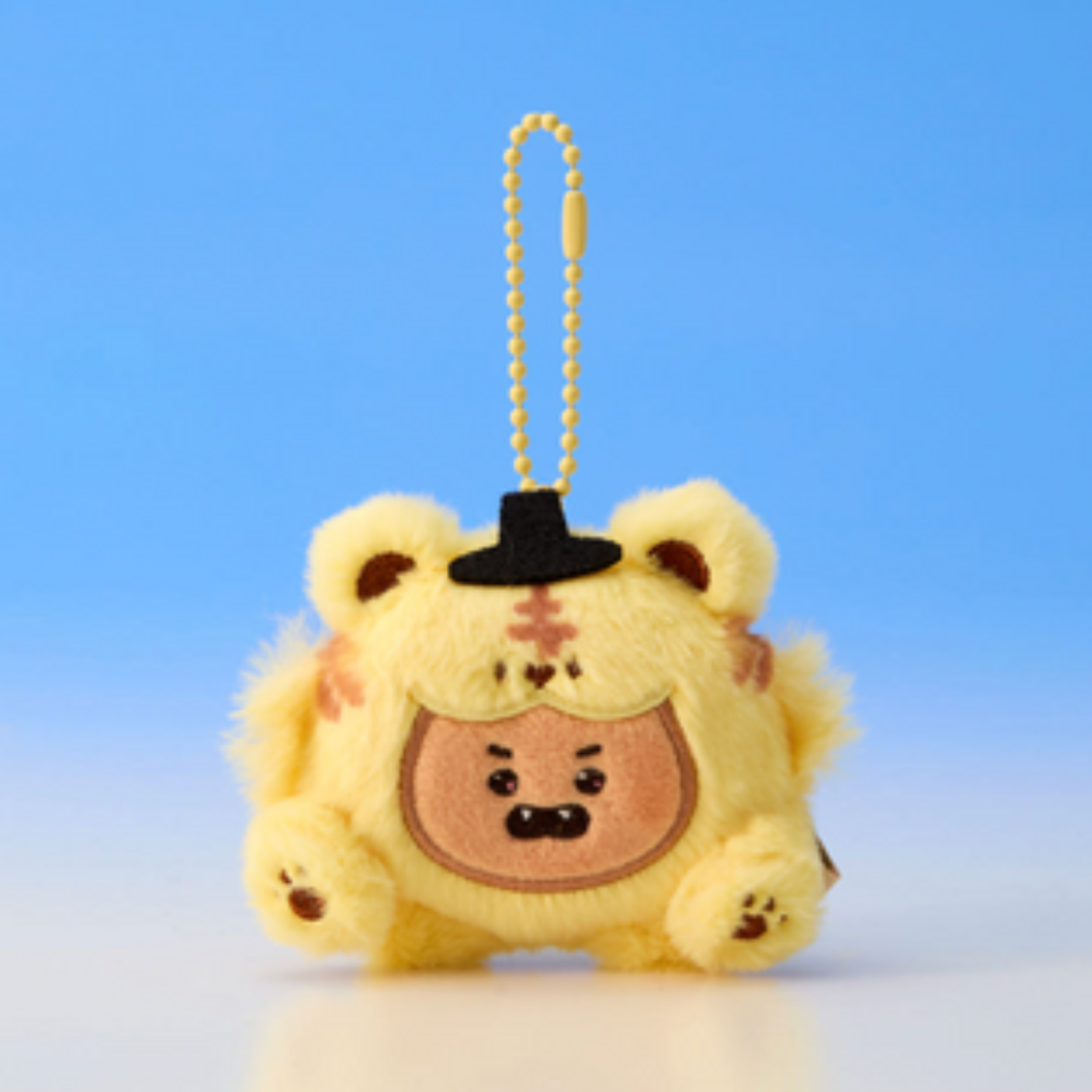 Plush keychain of a cartoon character with a black hat on a blue background