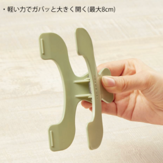 Hand holding a green book clip against a beige background