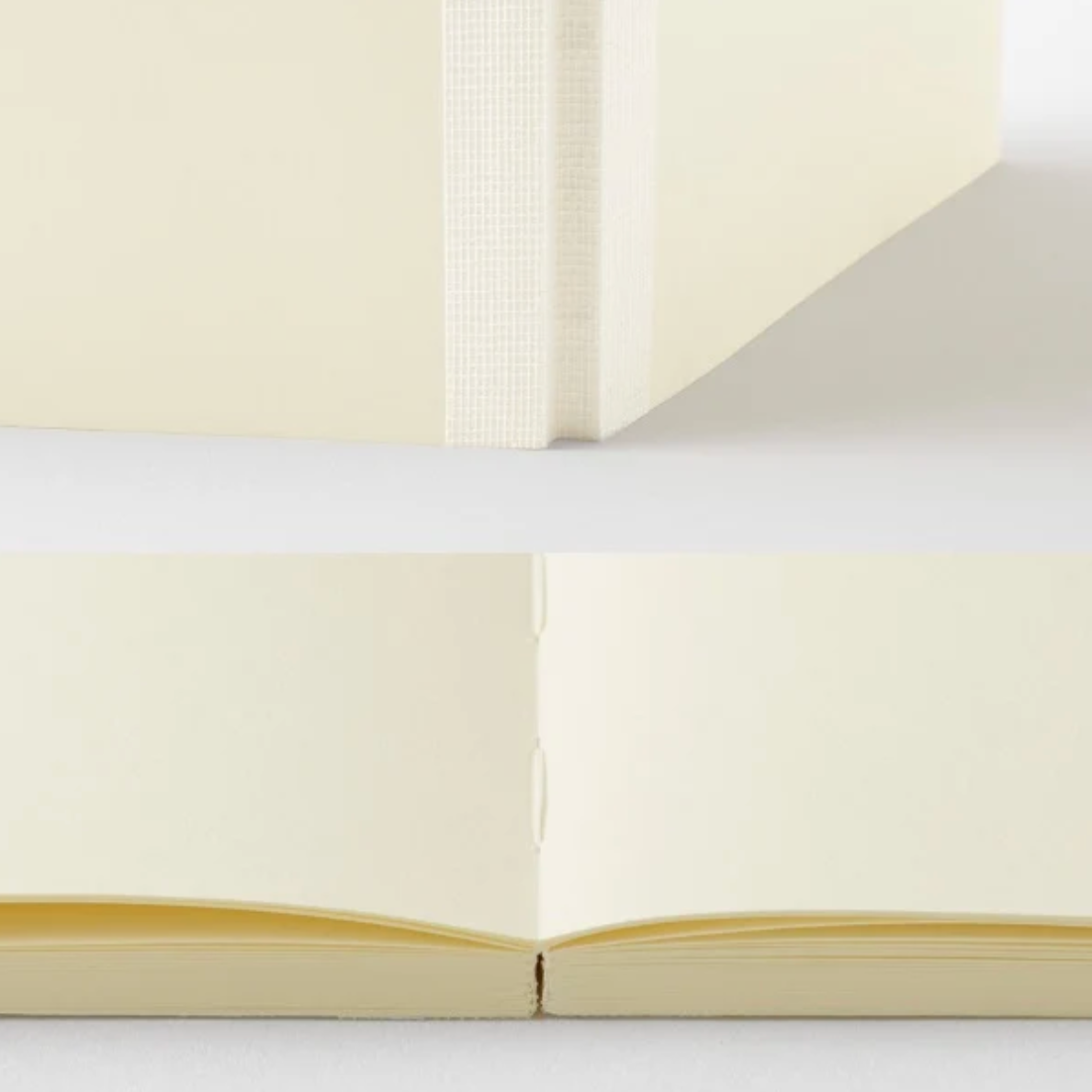 A close-up product photo of a cream-colored notebook or journal, showing the spine, page edges, and open spread of the pages against a clean white background.
