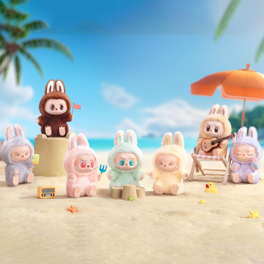 Toy figures of bunnies in various colors on a beach with a clear blue sky.