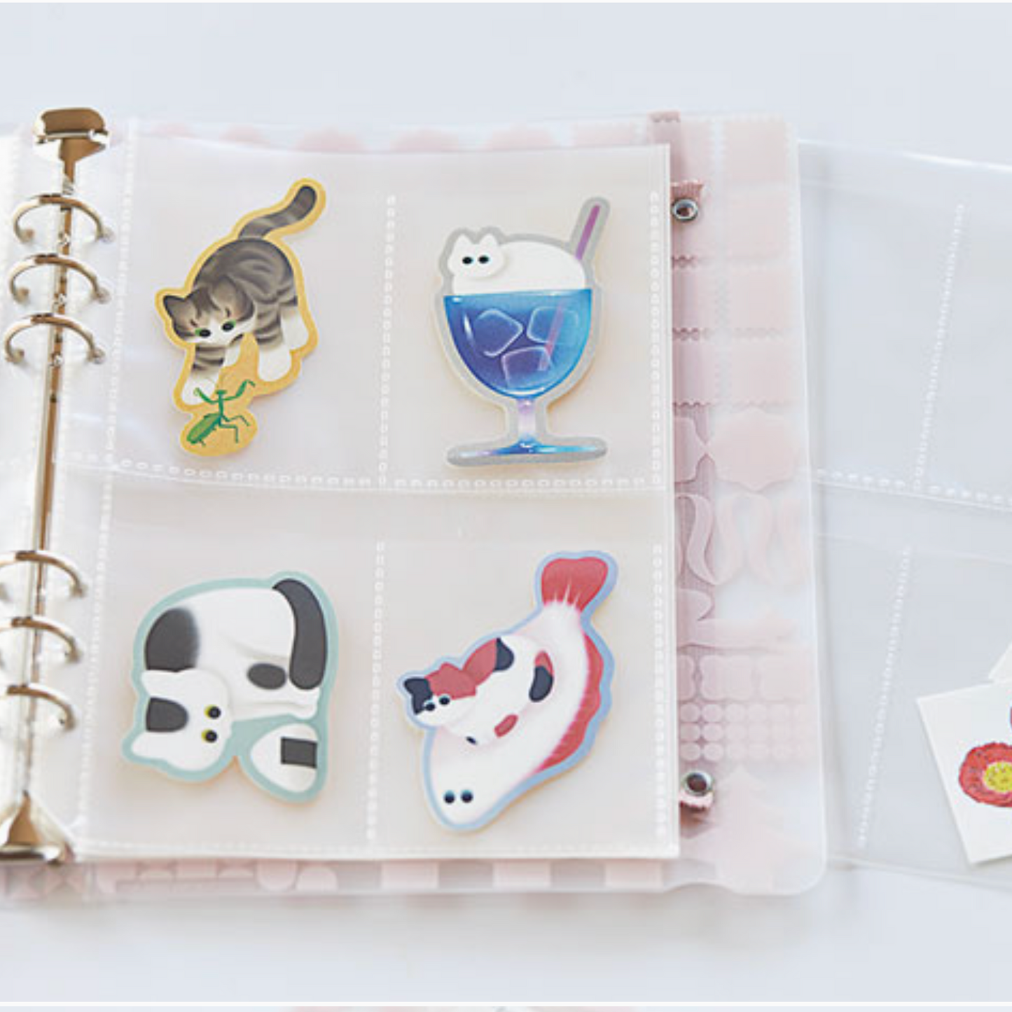 Sticker album with various stickers including a cat, ice cream cone, and panda on a white surface.