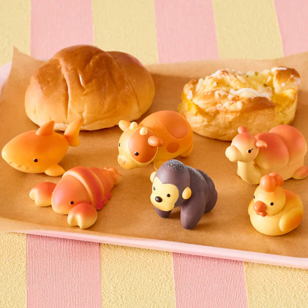 Wooden tray with bread-shaped animal figures on a striped pink and yellow background
