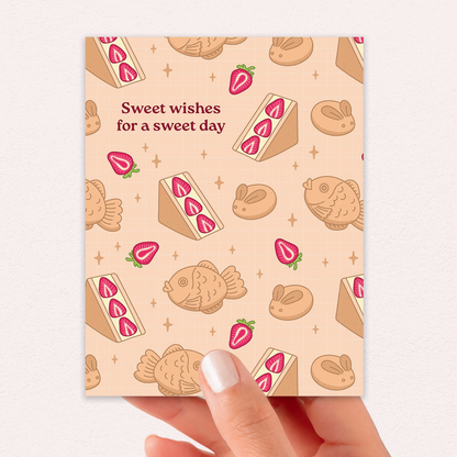 Card with dessert illustrations and text 'Sweet wishes for a sweet day' held by a hand.
