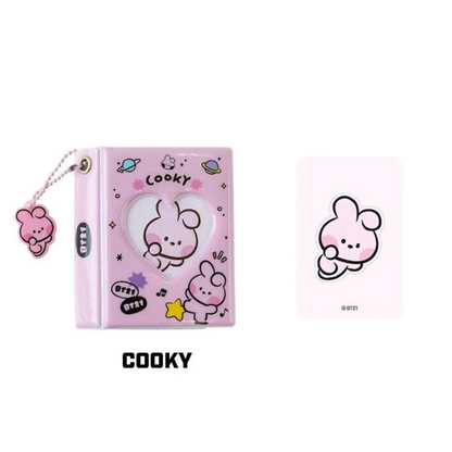 Pink photo album with heart window, and ball keychain with BT21 cartoon character 'COOKY' branding on a white background