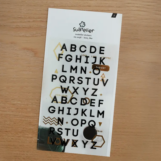 Sheet of black and white letter stickers on a wooden surface