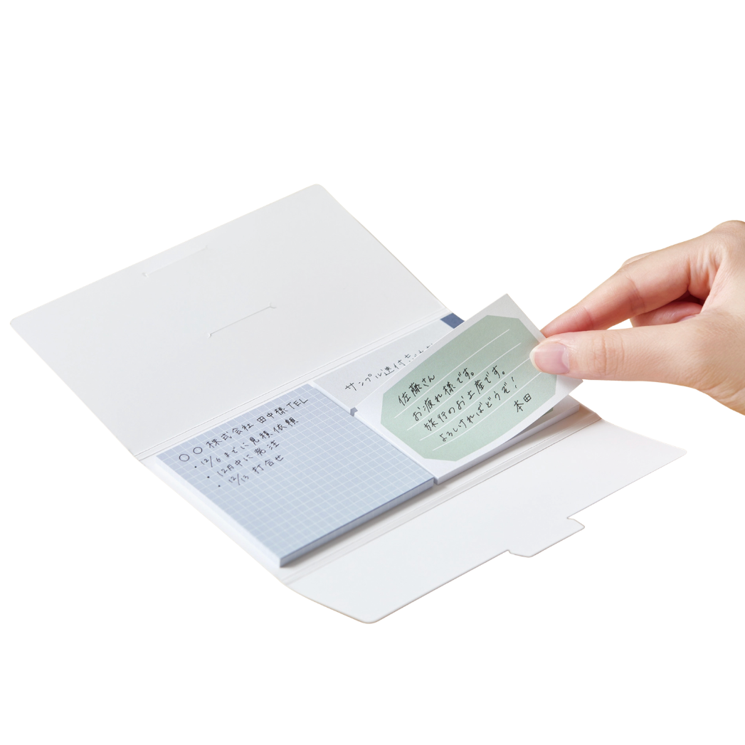 Hand holding a small notebook with a green label on a white background