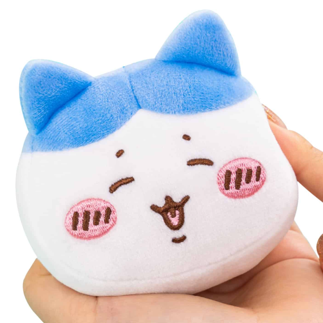 Plush toy with a blue bow and cartoon face held in a hand against a white background