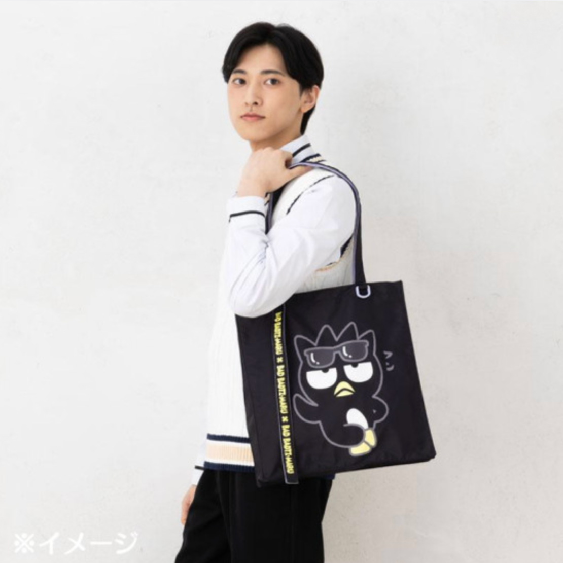 Person holding a black tote bag with a cartoon character design on a white background