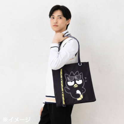 Person holding a black tote bag with a cartoon character design on a white background