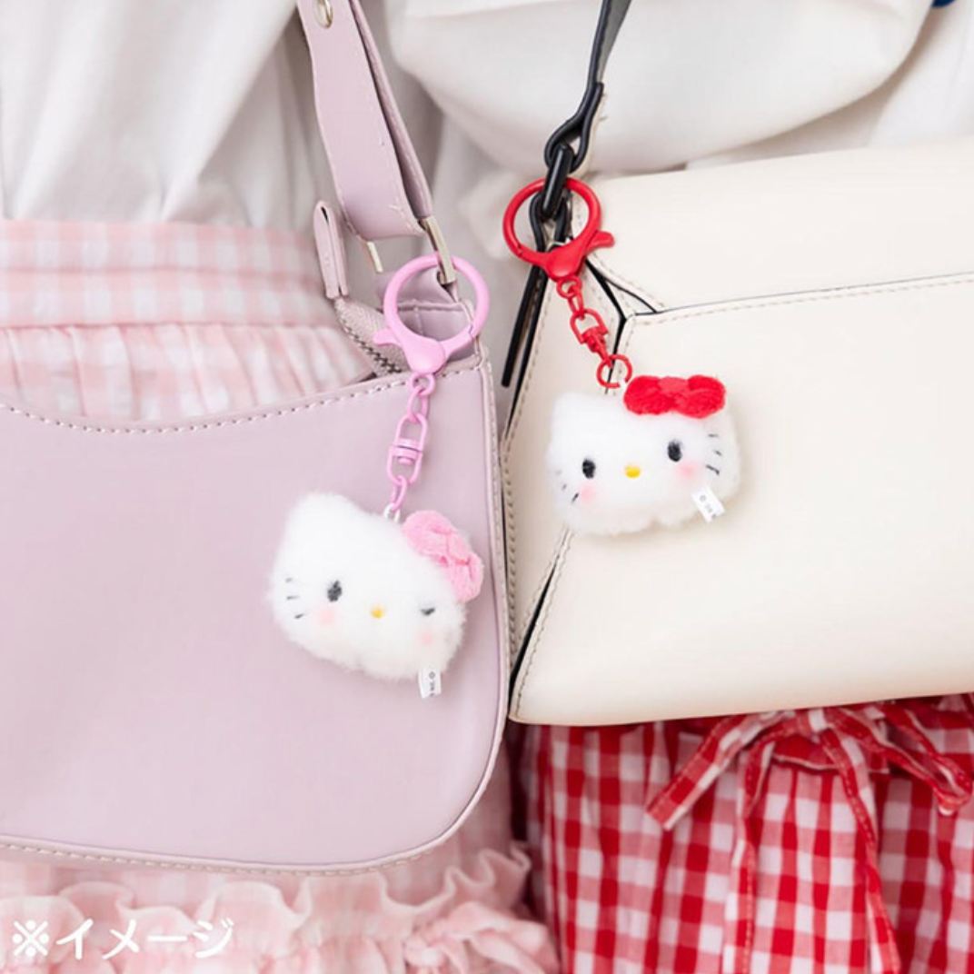 Two Hello Kitty keychains attached to a pink bag and a white bag with a checkered skirt.