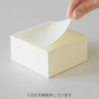 White cube being held by a hand on a light gray background