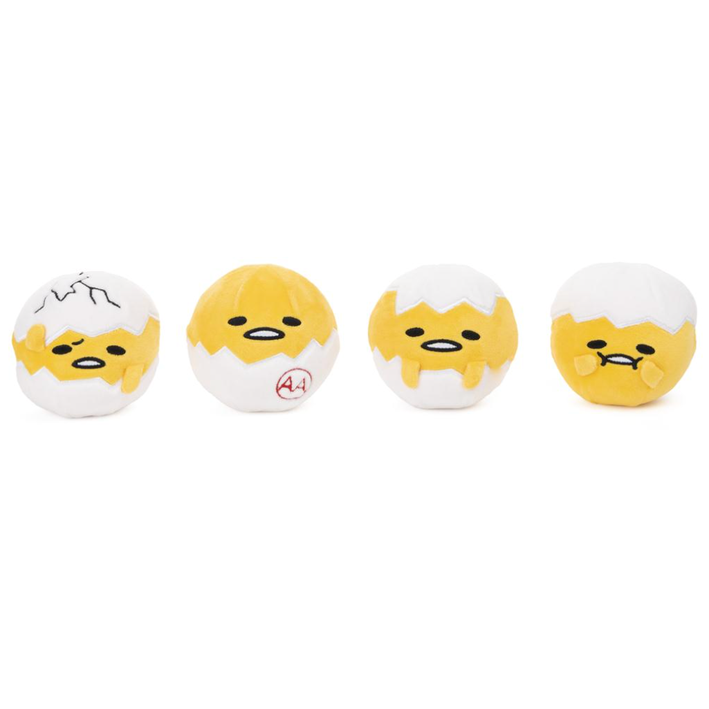 Four small plush egg-shaped toys lined up on a plain white background. Each toy has a yellow face and body peeking out from a white cracked eggshell, with different facial expressions and small red markings on some shells.