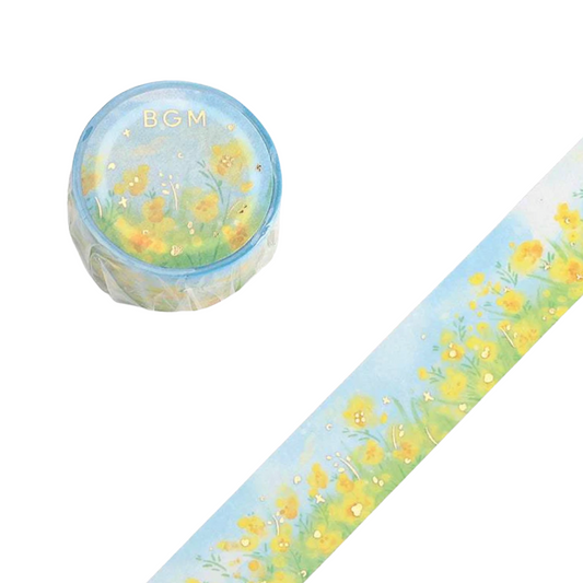 A roll of decorative washi tape with a watercolor-style yellow flower field pattern on a light blue background, shown with the unrolled strip and the rolled-up end. The rolled end has the letters 'BGM' printed on it.
