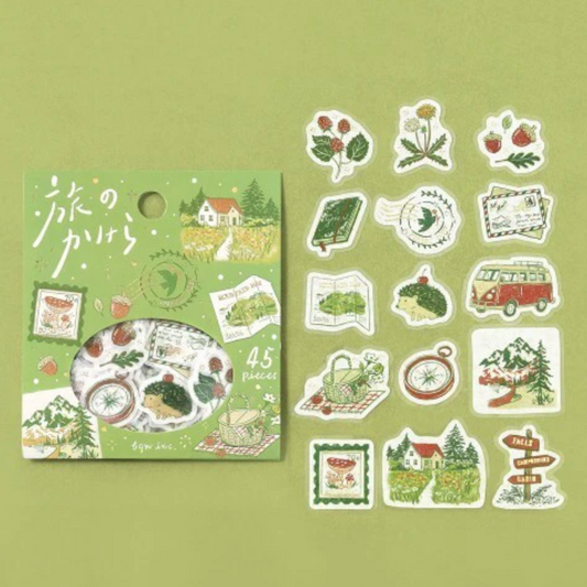 A sticker set package with a circular window showing assorted travel-themed stickers, alongside twelve individual stickers displayed on a light green background. The stickers feature illustrations of strawberry fields, a vintage camper van, a map, a compass, a notebook, a postcard, a house, trees, and directional signs in soft green, cream, red, and brown tones.