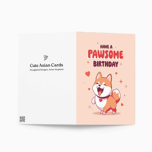A folded greeting card shown against a light gray background. The front features a peach panel with the text 'HAVE A PAWSOME BIRTHDAY' and a cute cartoon dog character.