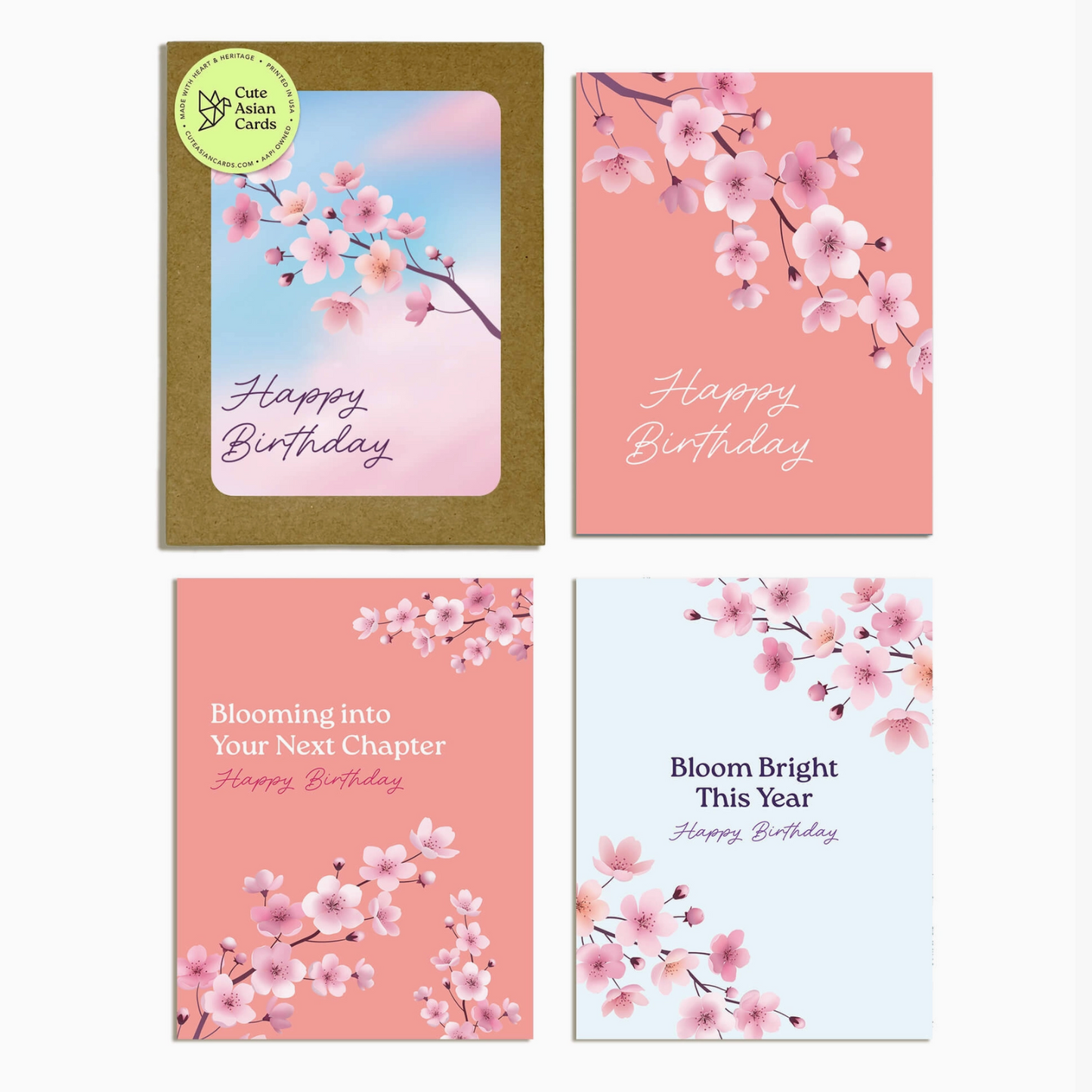 Four birthday cards arranged in a 2x2 grid on a light gray background. The cards feature pink and peach cherry blossom illustrations, with one card showing a gold envelope and a green circular 'One Card Magic' sticker.