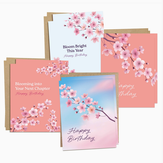 A set of birthday greeting cards with pink cherry blossom illustrations, shown with kraft paper envelopes on a light gray background.