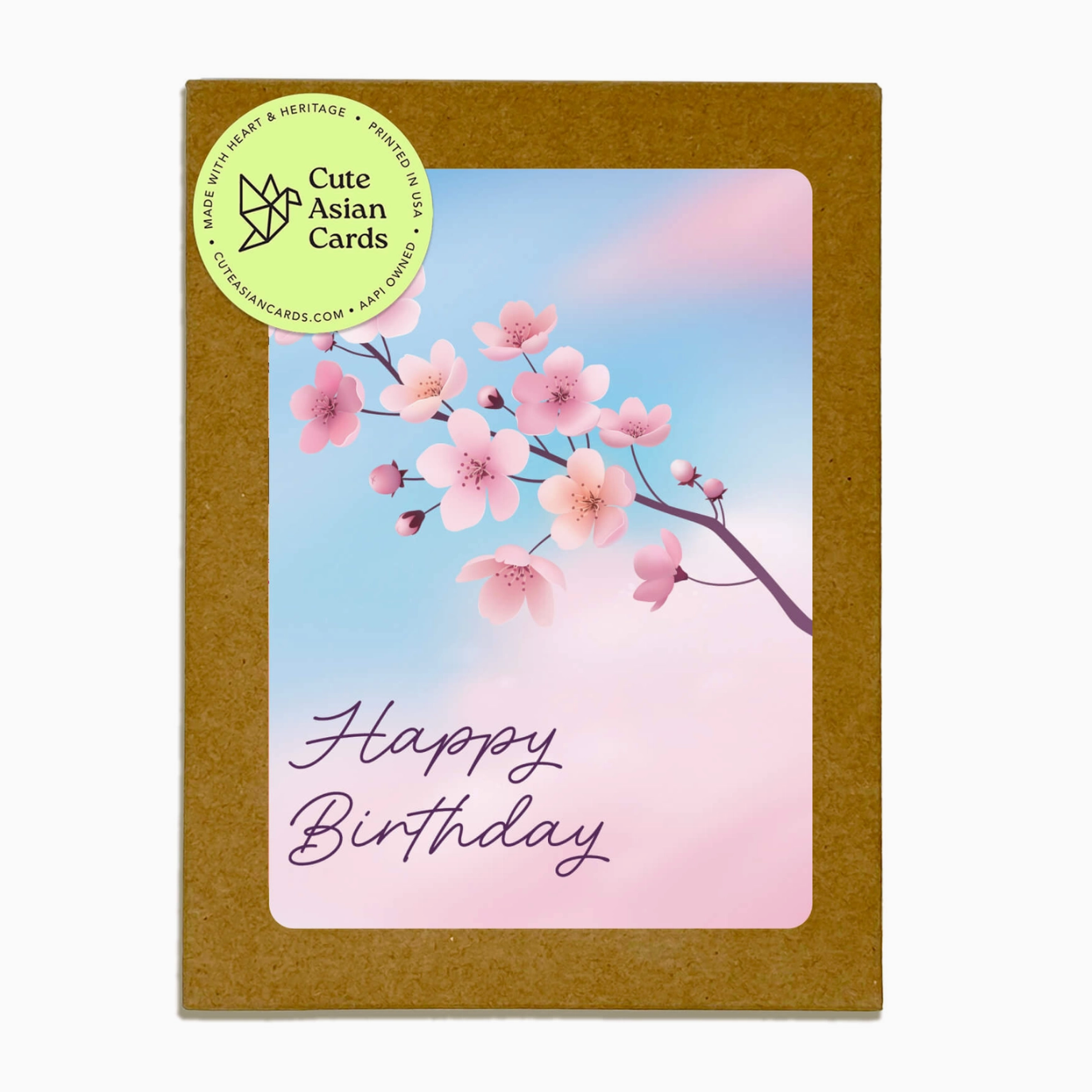 A square Happy Birthday card with a brown kraft paper border and a central illustration of pink cherry blossoms against a soft blue and pink gradient background. The words 'Happy Birthday' are written in purple script.