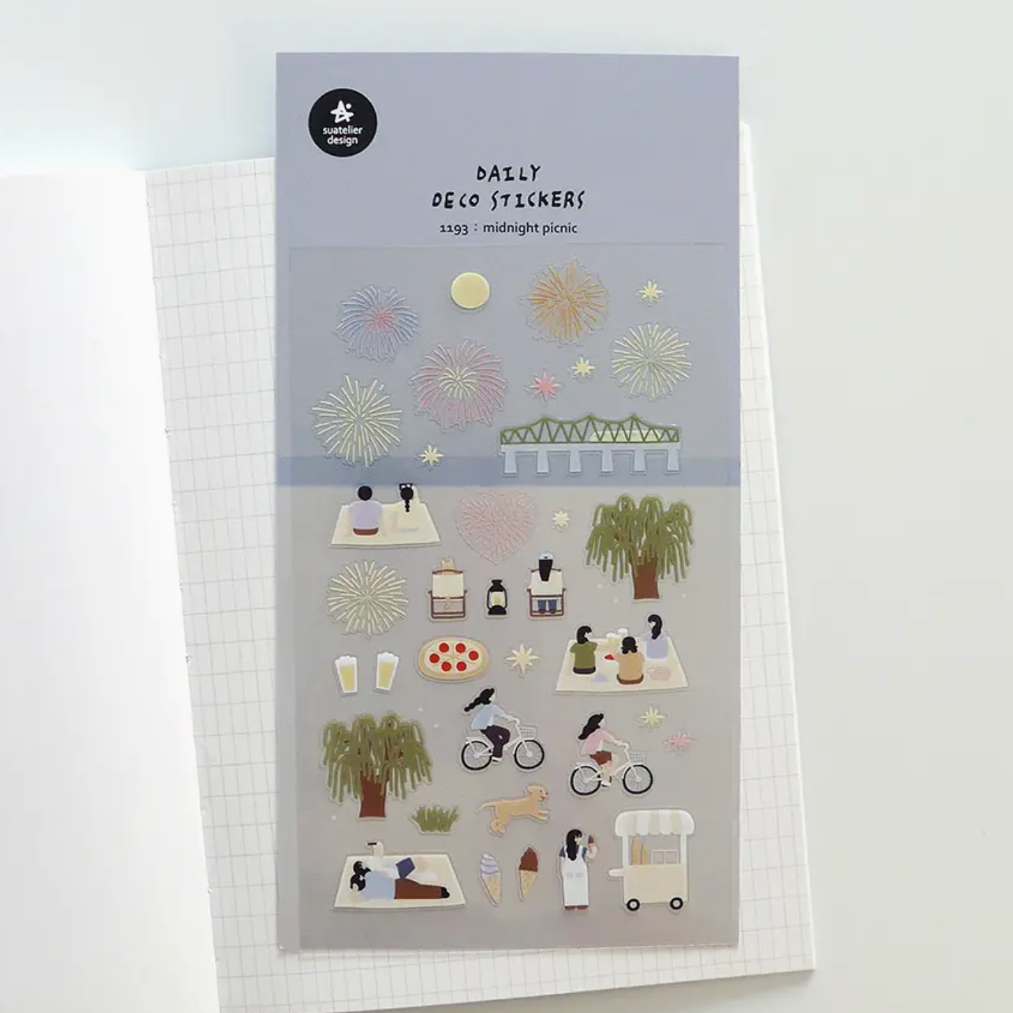 A sheet of daily desk stickers featuring minimalist illustrations of people, bicycles, trees, and picnic scenes, displayed on a white grid notebook.