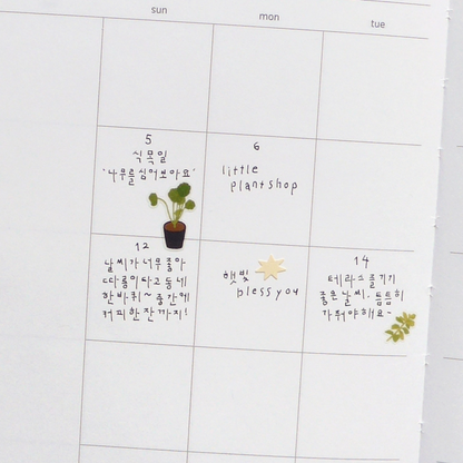A white daily planner or calendar page with columns for sun through wed and handwritten notes in French and Korean, on white calendar background.