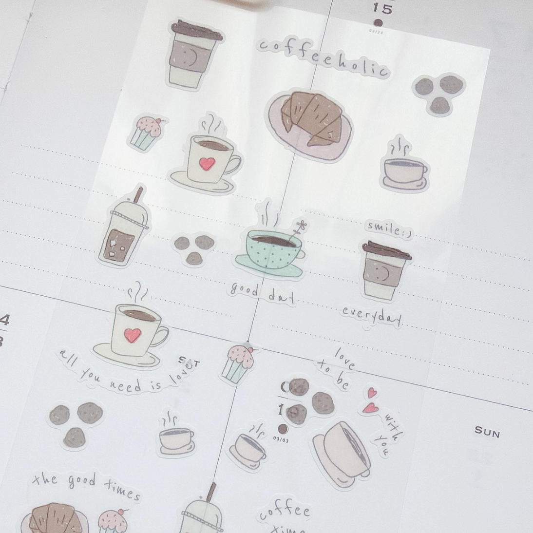 A sheet of cute coffee-themed planner stickers displayed on a white dotted planner page. The stickers feature hand-drawn illustrations of coffee cups, pastries, and coffee beans in soft pastel colors, with handwritten labels like 'coffeekotic', 'smilej', and 'good day'.