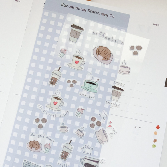 A sheet of cute coffee-themed planner stickers by Kubaandlucy Stationery Co, featuring illustrations of takeaway coffee cups, croissants, cupcakes, and handwritten text like 'coffee addict' and 'good day!' on a light blue and white gingham background.