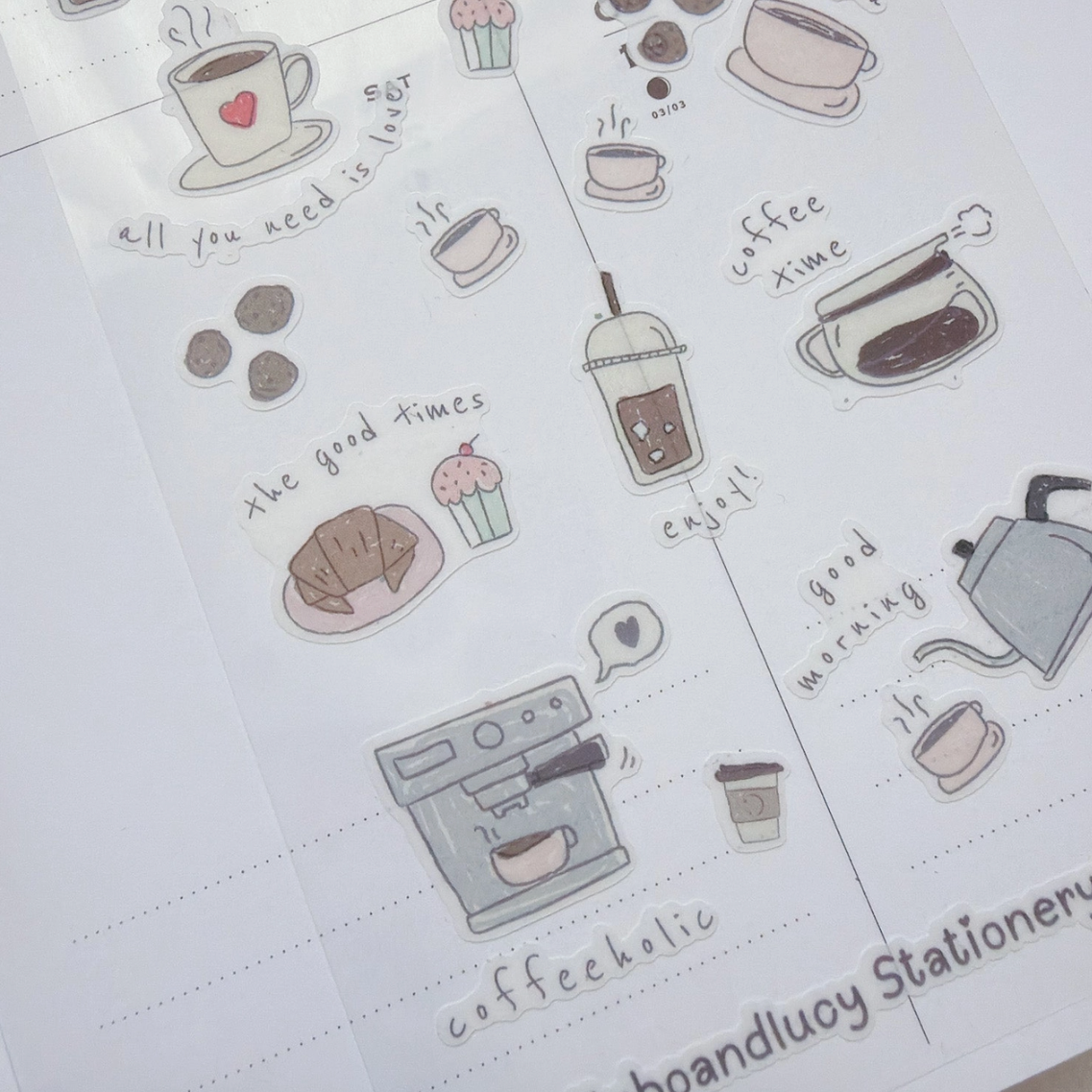 A close-up of a stationery sheet featuring cute coffee-themed illustrations, including mugs, an espresso machine, a cupcake, and handwritten phrases like 'coffee time' and 'good mornings'.
