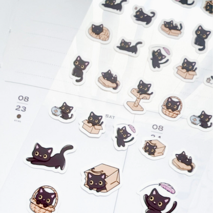 A sheet of cute die-cut stickers featuring black cats in various playful poses, displayed on a white planner page.