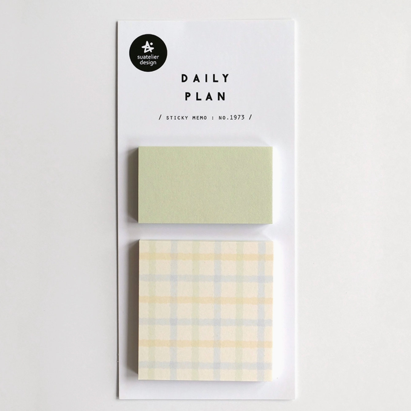 A daily planner sticky note set by Paper Garden on a white backing card, featuring a solid pale sage green note and a pale yellow and blue plaid note.