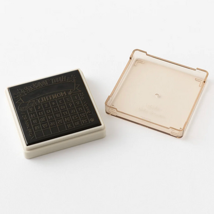 A square black rubber stamp with an embossed grid pattern and the word 'MUNTON' on the top, shown next to its translucent beige plastic cover on a white background.