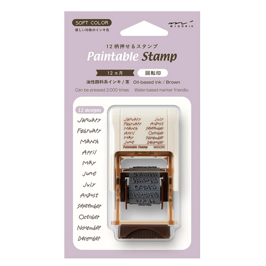 A packaged 12-month paintable ink stamp set by Mizunin, featuring a clear plastic case containing a wooden-handled stamp with brown oil-based ink, shown on a light lavender background with printed month labels and product details.