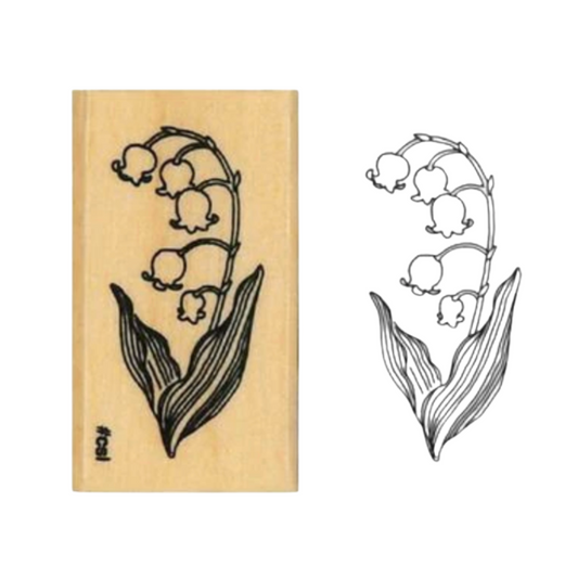 A wooden rubber stamp with a lily of the valley floral design, shown next to its corresponding inked stamp impression on a plain white background.