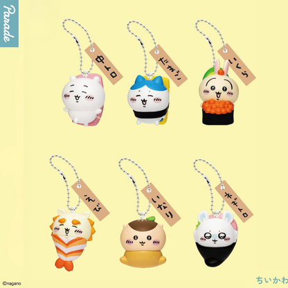 Six cute plush keychain charms arranged in two rows on a pale yellow background. Each charm has a small paper tag with Japanese text and a metal chain.