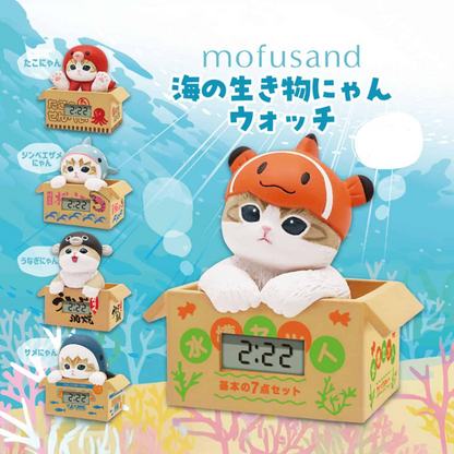 A set of five small cat figurines in cardboard boxes, each wearing a different sea creature hat, with a larger orange clownfish hat on the front box. The text 'mofusand' and Japanese text appear on a light blue underwater-themed background.