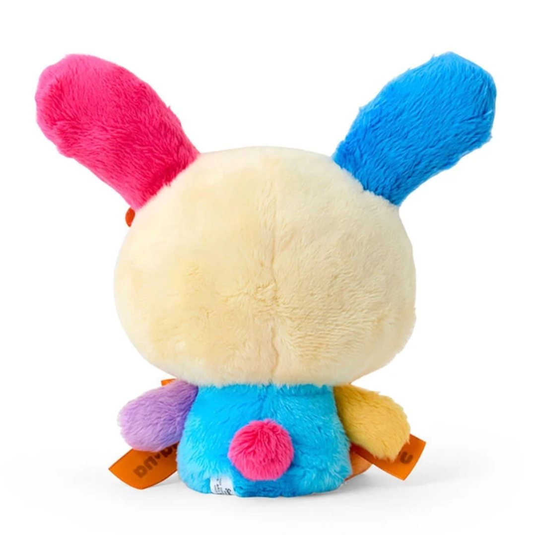 A plush bunny toy shown from the back, featuring a cream-colored body, bright pink and blue ears, and a blue back with small multicolored accents, photographed on a white background.