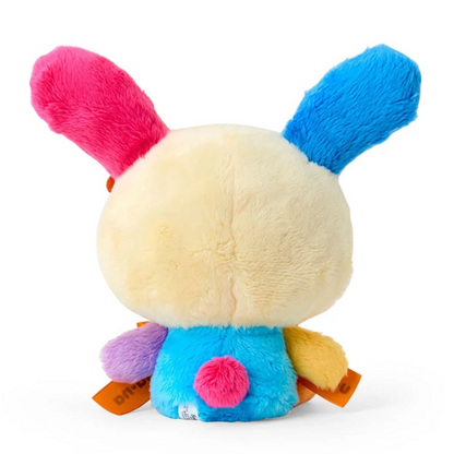 A plush bunny toy shown from the back, featuring a cream-colored body, bright pink and blue ears, and a blue back with small multicolored accents, photographed on a white background.