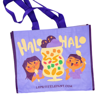 A light purple reusable tote bag with dark purple handles, featuring a colorful cartoon illustration of a milkshake and the text 'HALO HALO' and 'LEPETITELEFANT.COM'.