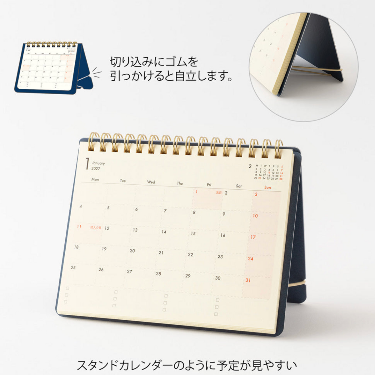 A spiral-bound desk calendar shown standing on its base, with Japanese callout text and inset detail images explaining its fold-out stand and gummed binding edge. The calendar page is cream with black text and red highlighted dates.