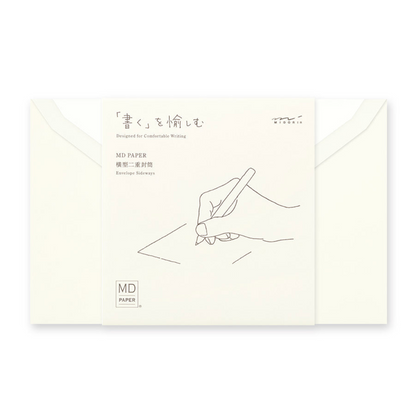 An off-white MD Paper envelope with a printed line drawing of a hand writing, shown with two matching envelopes behind it on a white background.