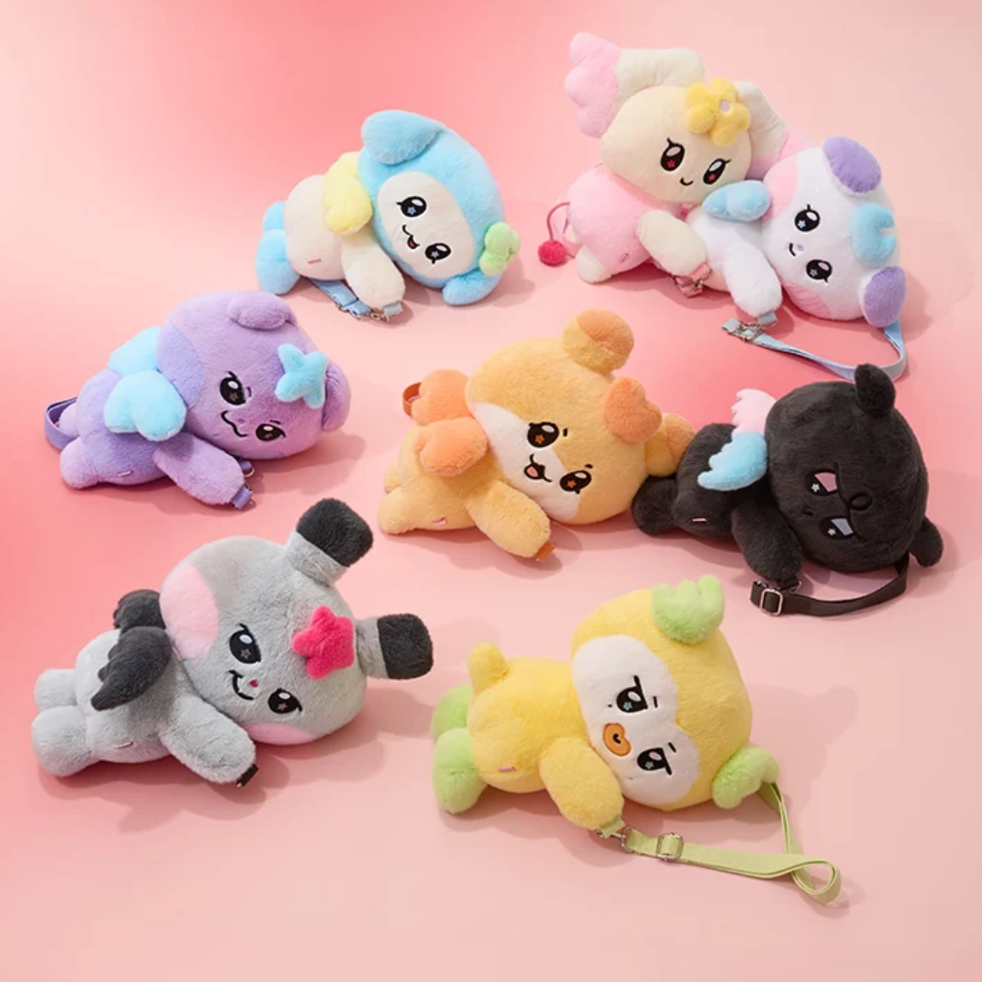 A set of eight cute cartoon plush toys arranged on a soft pink studio background. The plushies are in different colors including purple, blue, pink, yellow, orange, black, and gray, each with a small strap or leash attached.