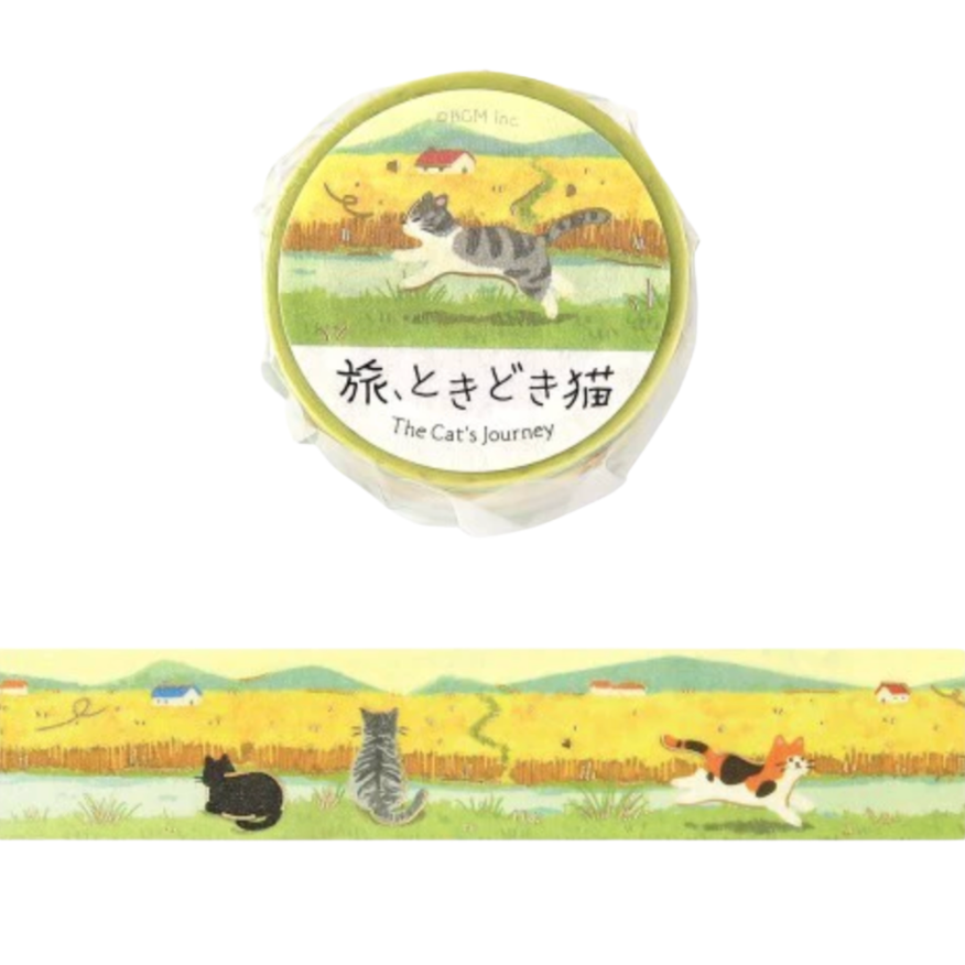 A round decorative item with a printed label reading 'The Cat's Journey' and Japanese text, shown above a matching illustrated strip featuring cats in a yellow field. The product appears to be a paper tape, sticker, or craft strip with a whimsical cat landscape design.