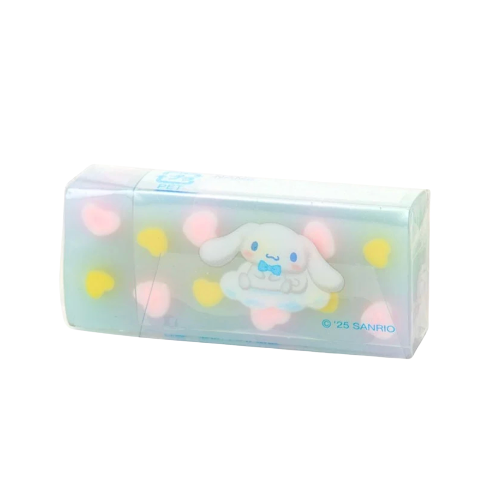 A Sanrio Cinnamoroll eraser in its clear plastic packaging, featuring a white cartoon dog with a blue bow tie, surrounded by pastel pink and yellow hearts on a white background.