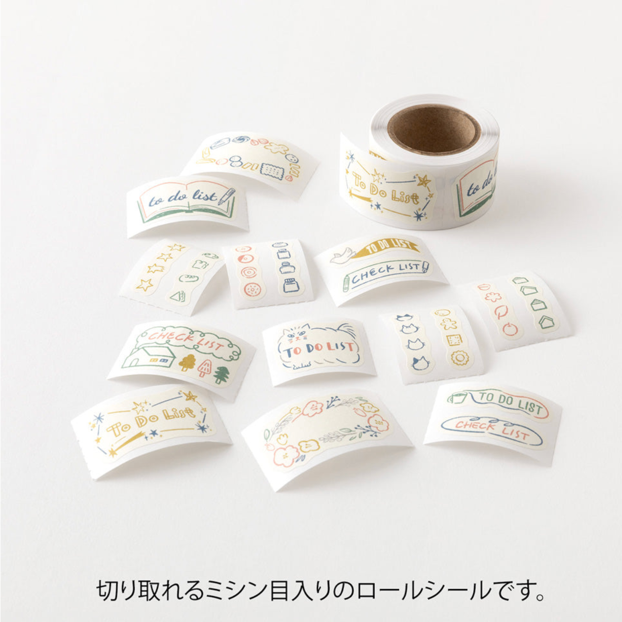 A roll of decorative adhesive stickers with French phrases and small doodles, shown with several individual sticker sheets scattered on a white background. Japanese text appears below the product photo.