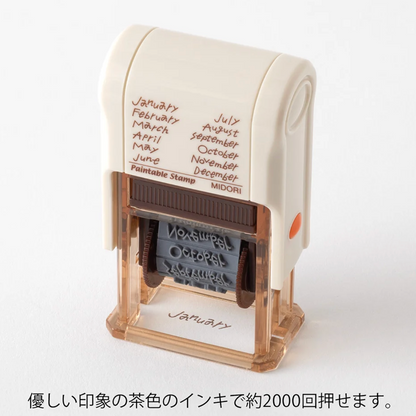 A self-inking stamp shown on a plain white background with Japanese text below. The stamp has a cream-colored top body, a clear plastic base, and a dark brown ink roller.