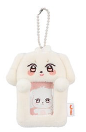 A plush dog-shaped phone pouch keychain in off-white, featuring a cute cartoon face and a clear window showing a smaller plush character inside. It has a silver ball chain attached at the top and a small orange tag on the side.